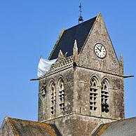 Gedenkteken voor de parachutist John Steele die met zijn parachute aan de toren is blijven hangen te Sainte-Mere-Eglise, Normandie, Frankrijk